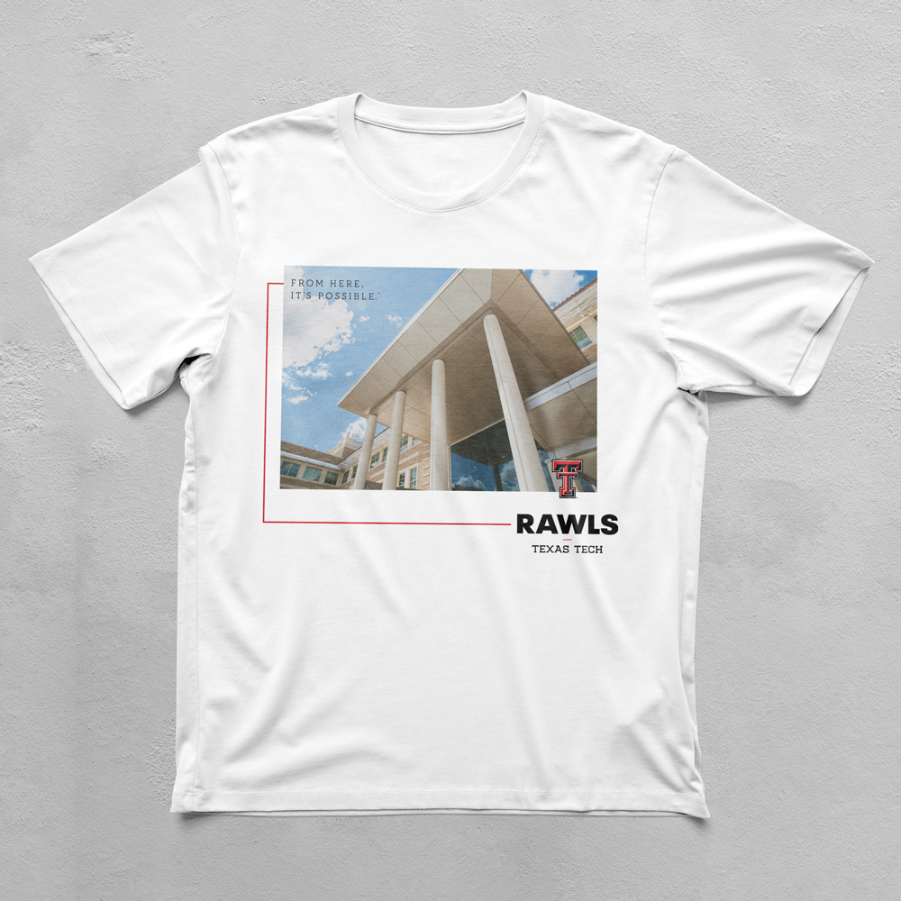 A white tshirt with a color photo of a building. The angle of           the photo is unique. Around the photo and slightly overlaid are           the Rawls Double T logo and From Here, It's Possible.