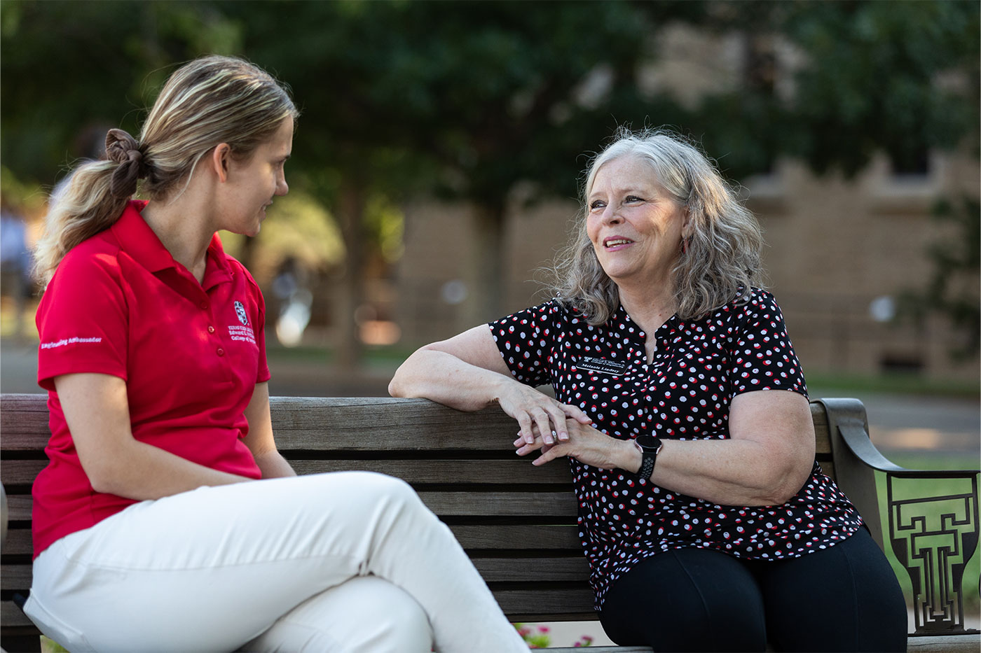 Melanie Lindsey, sitting on park bench talking to student