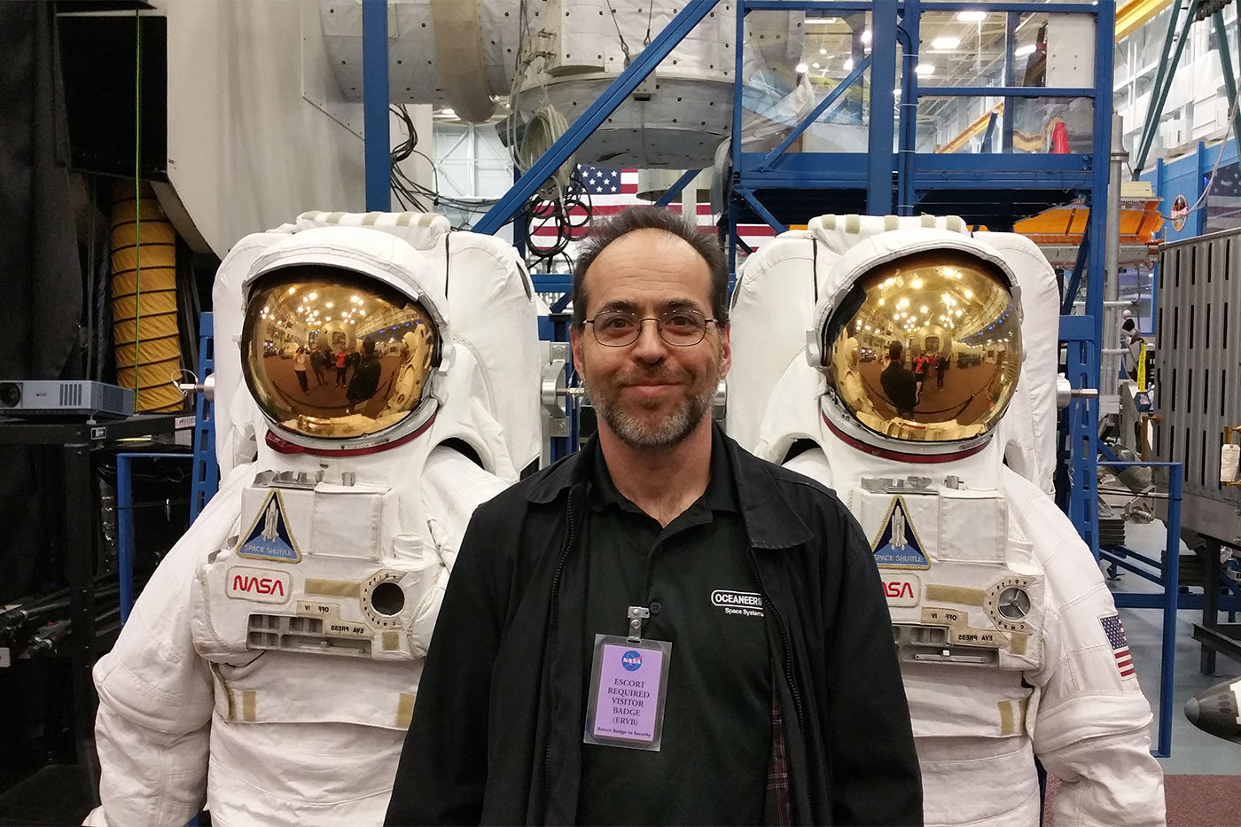 Rubin standing in front of two space suits. 