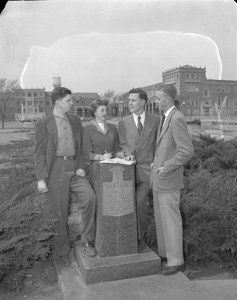 Four students stand around the Memorial Circle monument.