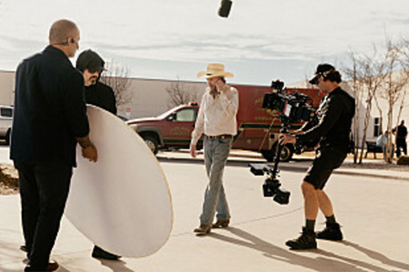 Camera crew filming Billy Bob Thornton as he walks down a street on his cell phone. 