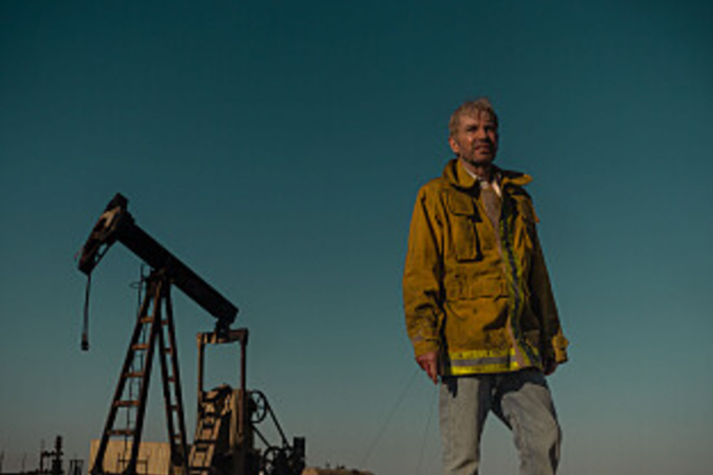 Billy Bob Thornton in front of pump jack. 